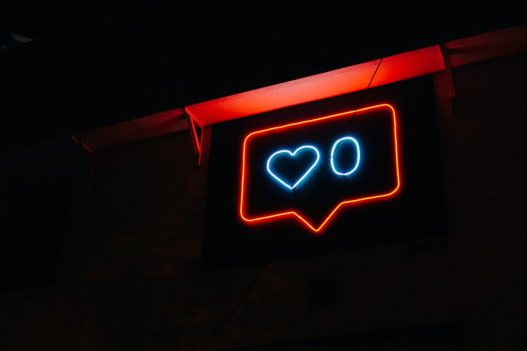 Red neon bubble speaking sign with a blue heart and a blue zero in the middle