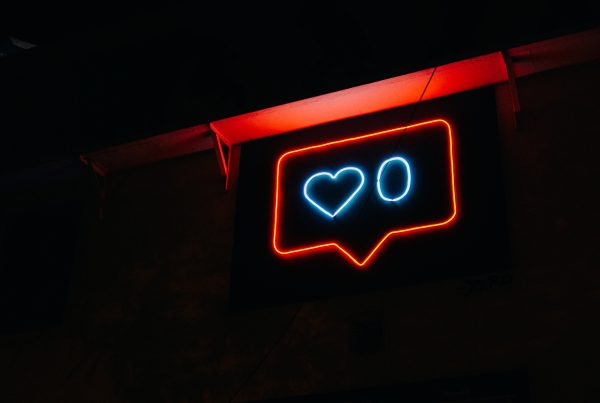 Red neon bubble speaking sign with a blue heart and a blue zero in the middle