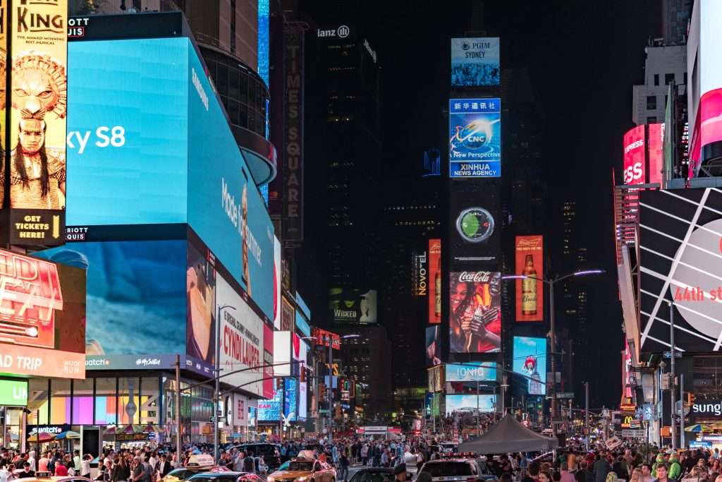 New York City's Times Square at night with billboard advertising all lit up with hordes of people lining the streets.