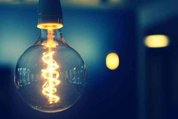 Spherical lightbulb with lit coil on the inside while hanging upside down