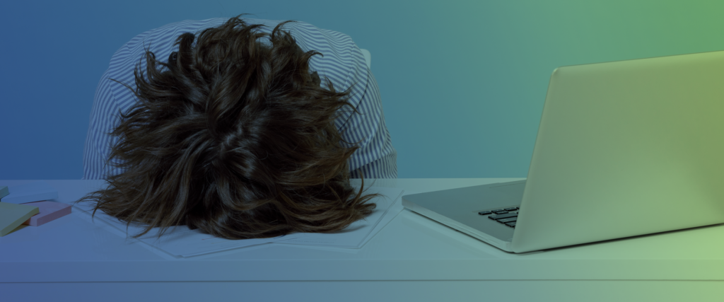 With a blue and green gradient background overlay, a person's head with brunette hair is face down on a table with a computer open on the person's left sid