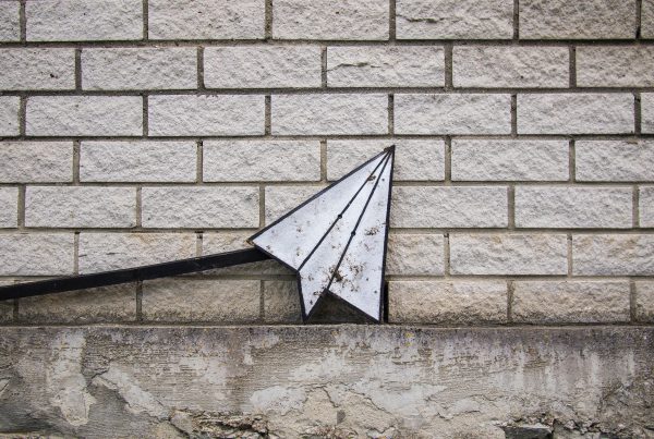 Paper airplane resting on a brick wall