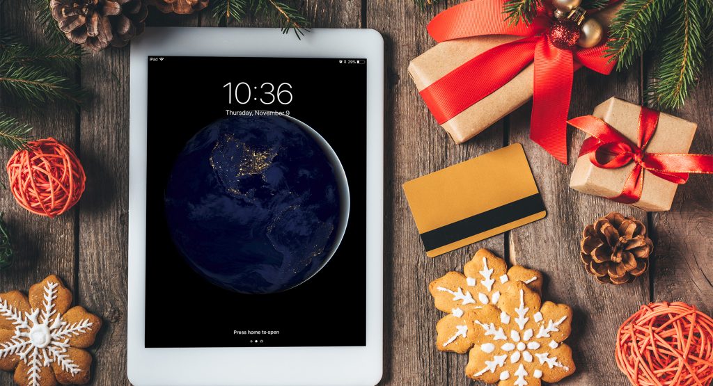 iPad with holiday decorations surrounding it as everything lays flat on a wood table