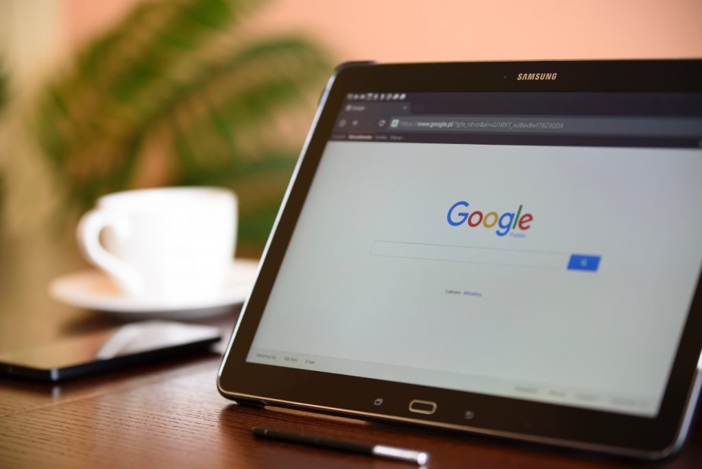 A Samsung tablet showing the front page of Google with a white coffee mug in the background
