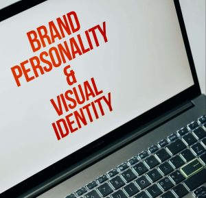 A Mac computer screen with a white background and all caps red letters saying brand personality & visual identity