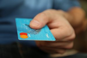 Person's hand handing over a blue credit card