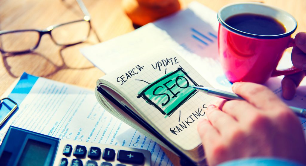 A person's drawing on a notepad that spells out "SEO"